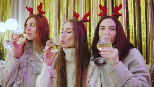 Three Young Women Toasting Christmas Champagne Indoors