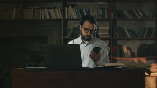 Man Working at Desk on Laptop and Phone