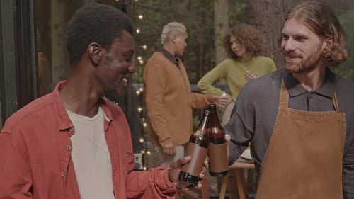 Friends Clinking Beer Bottles at Outdoor Gathering