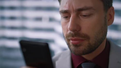 Serious businessman surfing internet using smartphone in modern office workplace