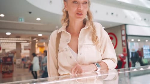 Elegant Woman Looking at Glass Display in Shopping Mall