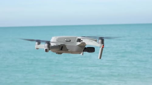 side view of drone hovering with ocean and blue sky in background