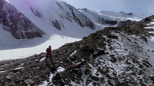 Lone Hiker Ascends Snowy Mountain Ridge