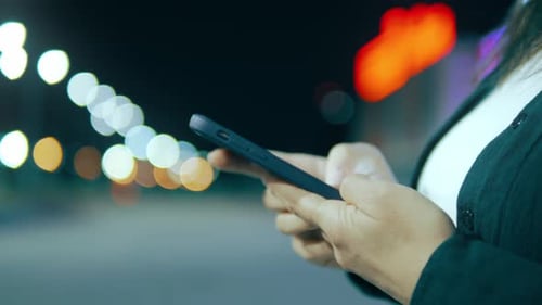 Woman Using Mobile Phone in City at Night