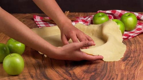Apple pie crust preparation on wooden surface