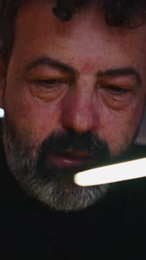 Technicien en électronique inspectant soigneusement un circuit imprimé à l'aide d'une lumière vive