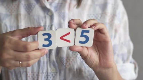 Woman Demonstrates Math Concepts with Numbered Tiles