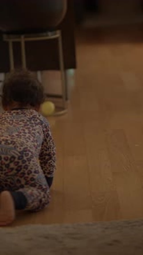 A Joyful Toddler is Crawling Around on the Floor While Dressed in a Colorful Playful Outfit