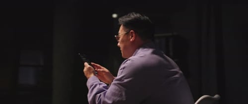 Close Up Asian Ethnicity Man with Glasses Use Mobile Phone Scrolling Social Media at Night Evening