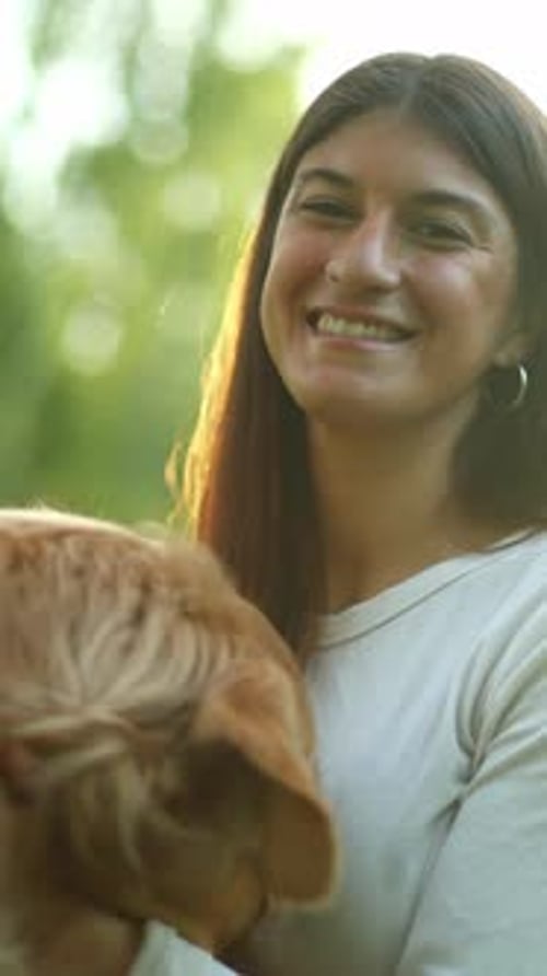 Smiling Woman Holding and Petting a Dog Outside