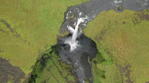 Aerial View of Small Waterfall Plunging into Dark Pool in Green Terrain