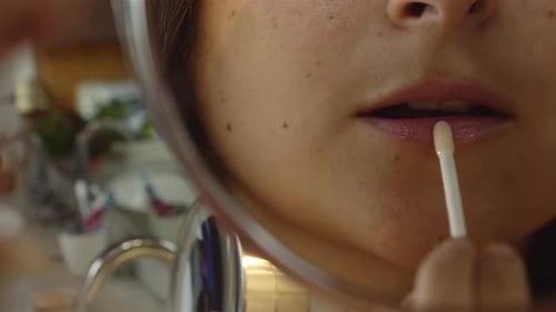 young woman putting on lip gloss on her lips with a mirror, Lip Gloss Application reflection. sexy l