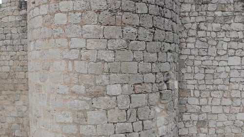 Close up view of the walls of an ancient castle, as the camera rises up and reveals the surrounding