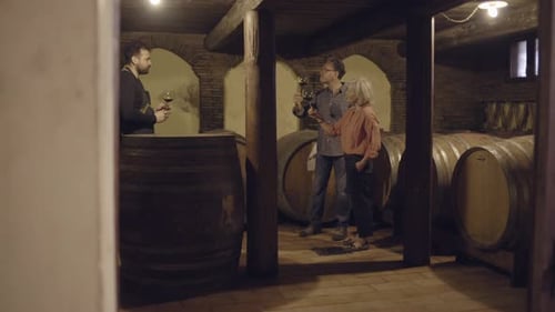 People Tasting Red Wine in Dark Wine Cellar