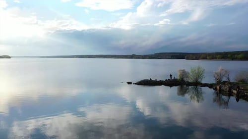 Beautiful river on nature landscape in spring. People rest near the water on stones in springtime.