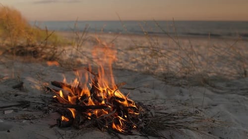 Lagerfeuer am Strand, das bei Sonnenuntergang an der Meeresküste brennt