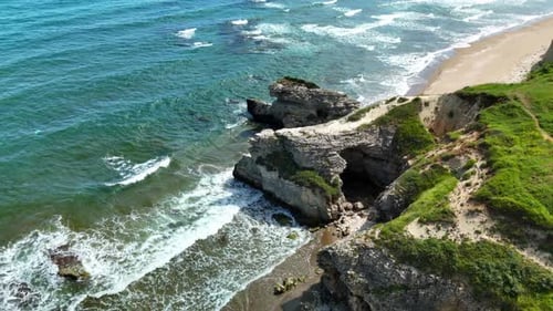 Breathtaking Aerial View of Ocean Cliffs and Waves on a Sunny Day