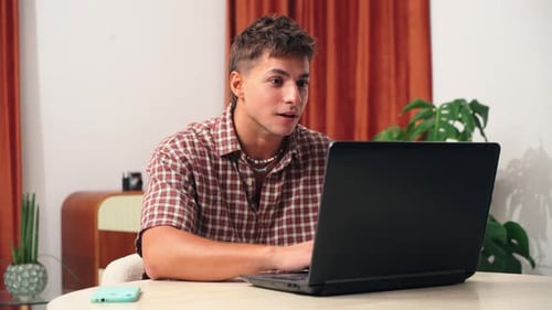 Excited Young Man Using Laptop Celebrates Success
