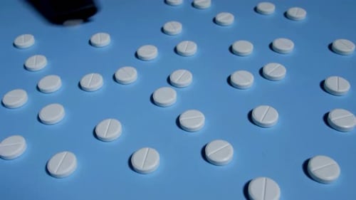 Pills Being Swept Off of a Light Blue Surface