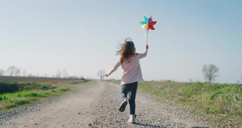 Energetic Child Runs with Pinwheel on Rural Road