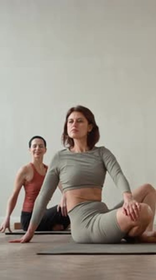 Women Doing Yoga Stretches Together in Fitness Studio