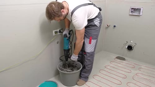 Construction Worker Preparing Tile Surface Mixing Mortar Substrate for Flooring Underfloor Heating