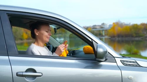 Woman Knitting Yellow Yarn Inside Parked Car