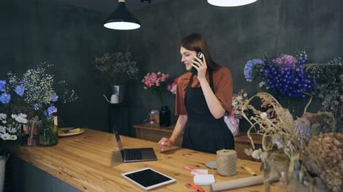 Woman Florist Owner of a Flower Shop is Talking with a Customer on the Phone Small Business Selling