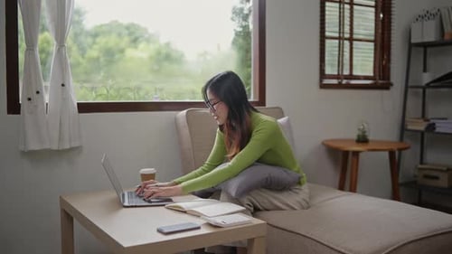 Woman wears green sweater working studying and liniving at home.