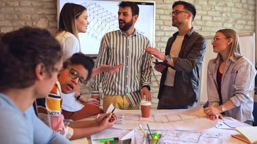 Group of young business people discussing architectural designs in office.