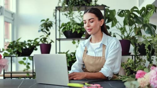 Young Woman Working on Laptop Surrounded by Plants