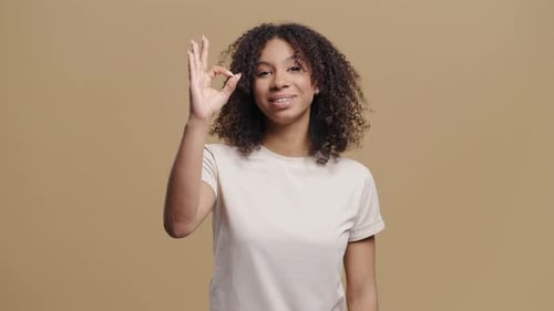 Une femme africaine positive forme un signe de la main OK OKay, souriante et confiante, confirmation du succès