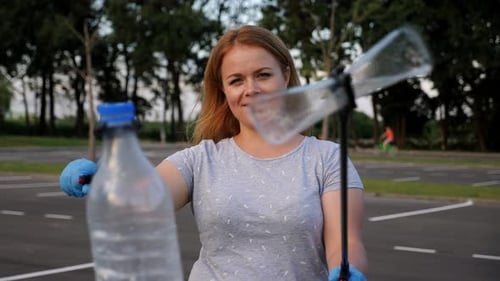 Woman Smiling While Holding Trash Grabber and Bottle