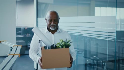 Mature Businessman Carrying Box of Office Supplies in Modern Corporate Setting