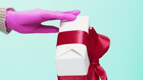 Gloved Hands Holding a Gift Box with Red Bow
