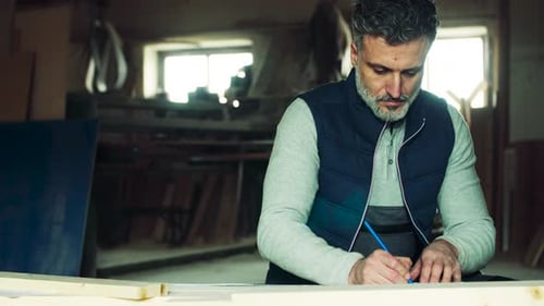 Man Worker in the Carpentry Workshop, Making Plans
