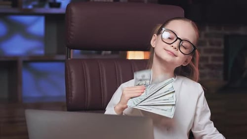 School Girl Sitting in Office Chair and Waving Dollar Bills