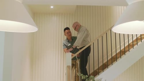 Young man helping senior man on staircase