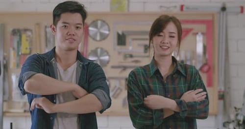 Smiling Man and Woman Stand with Crossed Arms in Workshop