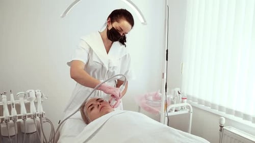 Cosmetologist Beautician Using Water Microdermabrasion Device During Procedure at Skin Studio Female