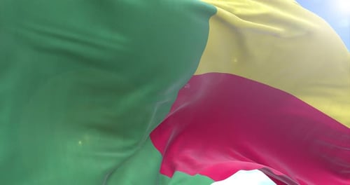 Realistic Waving Flag of Benin Against a Blue Sky