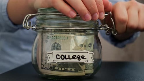 Unerkennbare Frau nimmt Geld vom Sparen in einem mit Dollar-Banknoten gefüllten Glasgefäß COLLEGE