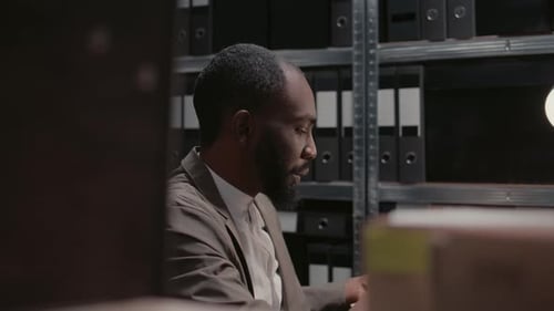 Man Sorting Through Files in a Dim Office