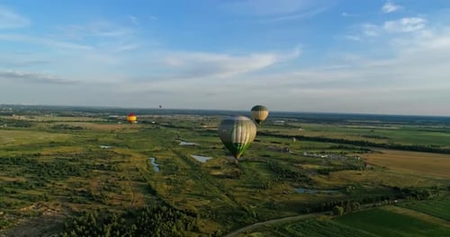 Beautiful aerostats in the air. Several colorful hot air balloons flying over green fields