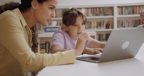 Teacher with School Child in Education Library using Laptop Technology