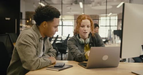 Two Gen Z Business People Meeting in Creative Office, using Laptop to discuss Ideas