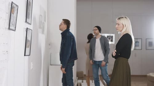 Men and Women in an Art Gallery Inspect the Abstract Works of Contemporary Artists