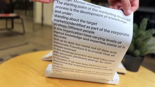 Close Up of Hands Holding Printed Paper with Strategic Market Analysis Text in Office