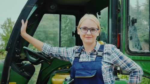 Woman Smiling Next to Green Tractor on Farm