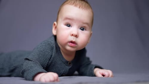 Un tout-petit de quelques mois a appris à garder la tête stable. Un enfant curieux regarde autour de lui, allongé sur son lit.